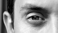 Detail of an eye of a handsome man looking at camera. Details of a male face, closeup. Black and white photo