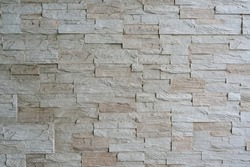 The walls for vintage style are decorated with uneven beige embossed narrow granite tiles.  old brown brick wall There are natural patterns on that brick. seamless surface uneven surface background
