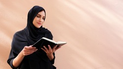 Female Arab college student reading her note book wearing Arab and Hijab traditional head scarf in the Middle East