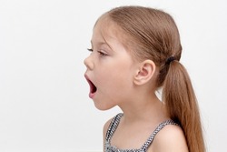 Caucasian little girl of 6 years with wide open mouth to show difficulty in speech, sound pronunciation and voice combined with impaired articulatory motility and speech breathing
