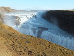 Gullfoss (Golden Waterfall) in Iceland on a beautiful sunny day, with a sharp shadow cast by the cliff and mist rising from the river