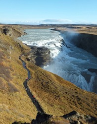 Footpath leading to Gullfoss Golden Waterfall in Iceland on a sunny day in autumn with the bright sunlight casting shadows on the river