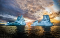 Two icebergs in the ocean at dawn. Iceberg at dawn. Beautiful sunrise over sea iceberg. Two iceberg at dawn