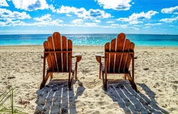 Two beach chairs on a sandy beach. Sandy beach scene. Two chairs on beach resort. Chairs on the beach