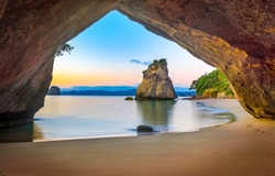 Sandy beach under the arch in the rock. Cave on rock beach
