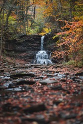 Serene waterfall surrounded by Autumn colors in October 2020 at Ricket's Glen State Forest.