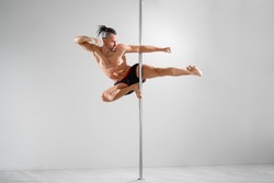 Fit pole athlete does trick on the pole, pole dancing 