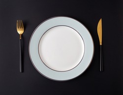 Serving empty plate with tableware at black background