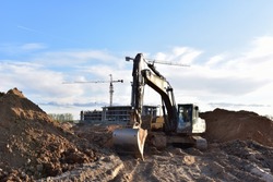 Excavator working at construction site on earthworks. Backhoe digging building foundation. Paving out sewer line. Heavy machinery for road work, excavating, loading, lifting and hauling of cargo