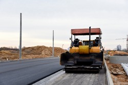 Asphalt paver machine during road work. Road Machinery at construction site for paving works. Screeding the sand for road concreting. Asphalt pavement is layered over concrete pavement. Road Surfacing