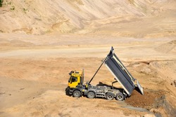 Dump truck unloading earth sand in quarry. Recovering the landscape around the open pit. Process of restoring land. Mine reclamation occurs once mining sand is completed.