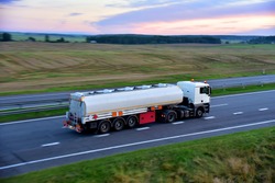 Isothermal Tank truck driving on highway. Oil and Gas Transportation and Logistics. Metal chrome cistern tanker with petrochemicals products. Liquid Chemical Freight. Soft focus possible granularity