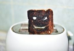 Burnt toast with an angry face expressing the emotion of sadness or sarcasm. Burnt toast bread slices out of a toaster. Сoncept of unsuccessful breakfast preparation before a work day or weekend