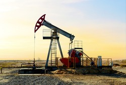 Crude oil pump jack at oilfield on sunset backround. Fossil crude output and fuels oil production. Oil drill rig and drilling derrick. Global crude oil Prices, energy, petroleum demand