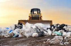 Garbage dump with plastic bags and food waste. Recycling of construction waste on junk yard. Refuse collection. Bulldozer dispose of rubbish at a landfill. Trash disposal area. Dozer on rubbish dump 