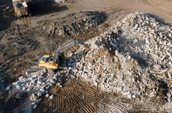 Recycling concrete and construction waste from demolition. Excavator at landfill of the disposa. Reuse of building rubble. Backhoe dig gravel at mining quarry on blue sky background. Out of focus