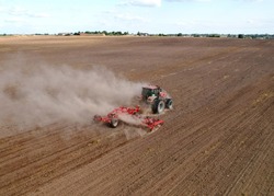 Cultivated land and soil tillage. Tractor with disc cultivator on land cultivating. Agricultural tractor on cultivation field. Tractor disk harrow on plowing field. Soil cultivation, Plough plowed.