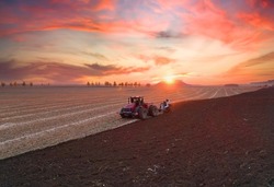 Tractor Plowing field on sunset. Cultivated land and soil tillage. Tractor with disc cultivator on land cultivating. Agricultural tractor on cultivation field. Tractor disk harrow on plowing field. 