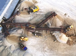 Sand Making Plant and Belt conveyor in mining quarry. Mining excavator loading sand in haul truck in opencast.  Sand crushing and bulk materials for construction industry. Open-pit mining.