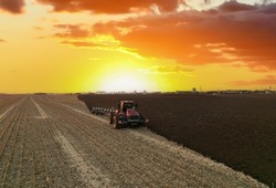 Tractor Plowing field on sunset. Cultivated land and soil tillage. Tractor with disc cultivator on land cultivating. Agricultural tractor on cultivation field. Tractor disk harrow on plowing field. 