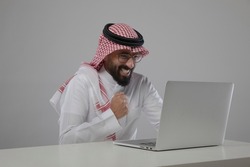 A saudi character using laptop so excited on white background
