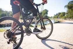 Close-up of person with disability on bicycle. Man with mechanical leg standing in park on sunny day. Sport, disability concept