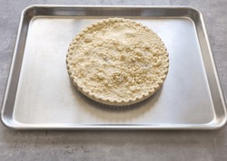 A ready made frozen Dutch apple pie on top of a baking pan.