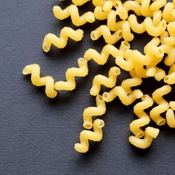 Pasta. Spiral macaroni. Raw uncooked macaroni isolated on black background, close up, top view.