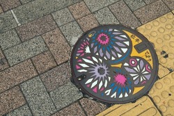 Decorative Japanese manhole cover depicting traditional handball craft. The letter on the cover means Matsumoto—name of the City and Temari—Japanese traditional handball craft.