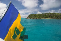 Flag of Saint Vincent and the Grenadines hangs off the stern of a sailing ship in the Tobago Cays