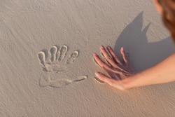 girl doing imprint with the hand in white sand