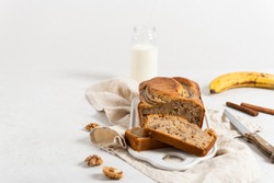 Homemade delicious banana cake with walnuts and cinnamon on white concrete background. Side view, close up. Bakery, recipe concept. Copy space. Selective focus