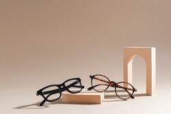 Two pairs of eyelass frames on beige background. Minimalism, summer fashion concept. Trendy eyeglasses still life in minimal stile. Optic store discount, sale. Copy space for text