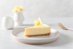 New York cheesecake or classic vanilla cheesecake with vanilla flower on a white stone background. Side view, copy space for text. Menu, recipe, confectionery