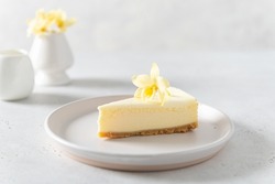 Homemade vanilla cheesecake with vanilla flower on a white background - healthy organic summer dessert pie cheesecake. Cheesecake New York. Side view, close up. Menu, recipe, confectionery