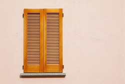 Beautiful wooden window shutter with windowsill, rosa painted cement wall and sunny day