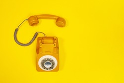 Yellow handset of a telephone on a yellow background. Modern retro style. New old technology. Concept of Color of the Year 2021 with bright illuminating yellow and gray colours.