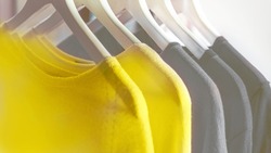 Bright illuminating yellow and gray colours clothes on hangers. Trendy colors of the year 2021 - Gray and Yellow. Fashionable clothes colors.