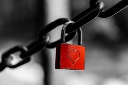 Red padlock with heart shape, locked, hanging on a chain. A symbol of love. 