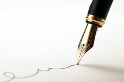 golden fountain pen leaves a signature on a white paper closeup