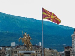 Macedonian flag with Skopje's landmark statue in background.
