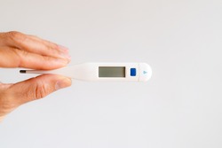 Hand holding a thermometer with a background white