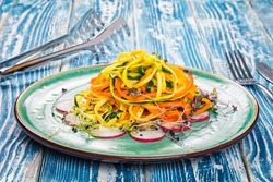 Vegetable pasta with carrot and zucchini. Served on a ceramic plate.