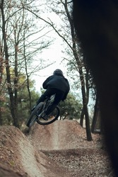 Downhill mtb cyclist descending and jumping down mtb trail at bikepark in catalunya, spain. Full black