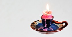 A bright candle in a vintage candlestick, illuminates a free space for creative design and writing metaphor text.