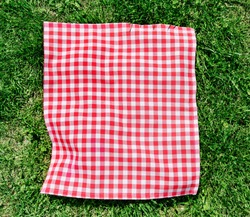 Red picnic cloth on grass top view.