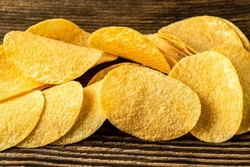 Potato chips on a wooden background. Salty crisps scattered on a table.