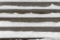 Front view of construction grey gravel concrete stairs covered with white snow in winter, Outdoor granite stair includes steps, Rough cement texture, Surface stone background.