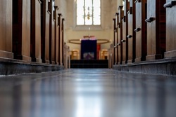 Corridor between the bench in the church with the sunlight, Inside the building with a row and lines of brown wooden pews in catholic church or chapel.