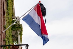 Official Netherlands flag with a school bag hanging outside the house along the street with blue sky, A tradition way in Holland when a student celebrate their graduates or Geslaagd in Dutch word.